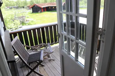 a rocking chair sitting on a porch looking out a door at Gamlestølen Fjellstue in Etnedal