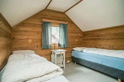 two beds in a room with wooden walls at Jorekstad Ferieleiligheter in Fåberg