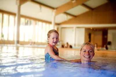 a woman and a child swimming in a swimming pool at Jorekstad Ferieleiligheter in Fåberg