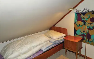 a bed in a room with a lamp and a table at 2 Bedroom Awesome Home In Tørvikbygd in Tyrvikbygd