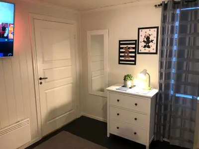 a bedroom with a white door and a dresser with a lamp at Vinstra Hostel in Vinstra
