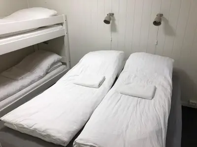 two beds in a room with white sheets at Vinstra Hostel in Vinstra