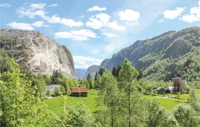 a green field with a barn in a mountain valley at Three-Bedroom Holiday Home In Vikanes in Eiknes
