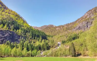 a green field in front of a mountain at Three-Bedroom Holiday Home In Vikanes in Eiknes