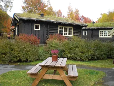 a wooden picnic table in front of a cabin at Vekve Hyttetun in Oppdal
