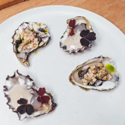 a white plate with three oysters on a table at Magic Kloverhuset Harbour Hotel, a member of Radisson Individuals in Bergen