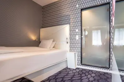 a small bedroom with a bed and a mirror at Magic Hotel Bergen City Center, a member of Radisson Individuals in Bergen
