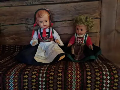 two dolls sitting next to each other on a bed at Rongen gard in Bolstadøyri