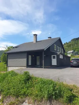 a black building with a car parked in a parking lot at Mørkve Apartement in Myrkdalen