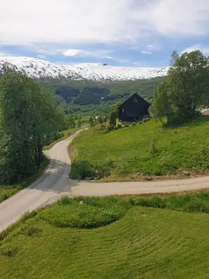 a road leading to a barn and a snow covered mountain at Mørkve Apartement in Myrkdalen