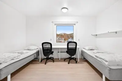 a room with two beds and a desk and a window at Namsos Hybelhus in Namsos