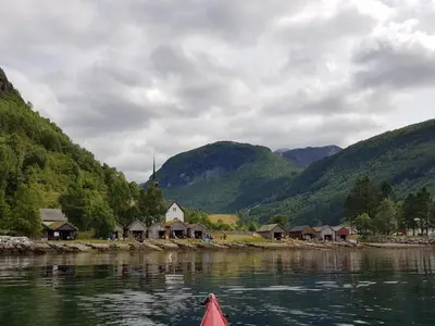 a boat in a body of water with mountains at Dalhus - House with jacuzzi in Norddal