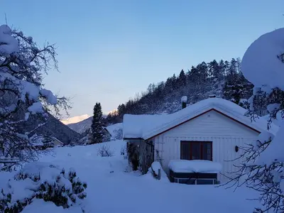 a small white shed covered in snow with trees at Dalhus - House with jacuzzi in Norddal