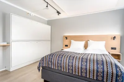 a bedroom with a bed and a closet at Birkebeineren Hotel & Apartments in Lillehammer