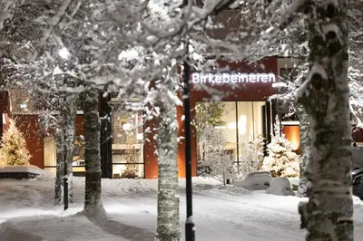 a street sign in the snow in front of a building at Birkebeineren Hotel & Apartments in Lillehammer
