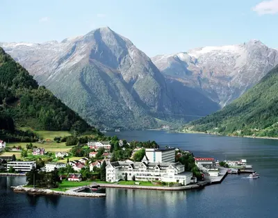a town on a island in a body of water with mountains at Kviknes Hotel in Balestrand