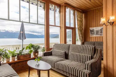 a living room with a couch and a large window at Kviknes Hotel in Balestrand