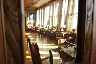 a dining room with tables and chairs and windows at Kviknes Hotel in Balestrand
