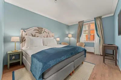 a bedroom with a large bed with blue walls at Hotel Breiseth in Lillehammer