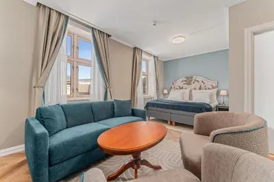 a living room with a blue couch and a bed at Hotel Breiseth in Lillehammer