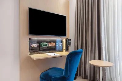 a room with a blue chair and a tv on a wall at Bergen Harbour Hotel, WorldHotels Crafted in Bergen