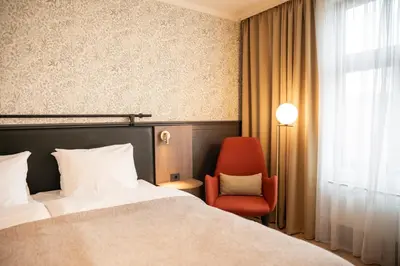 a hotel room with a bed and a red chair at Home Hotel Hammer in Lillehammer