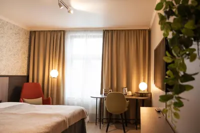 a hotel room with a bed and a desk and a window at Home Hotel Hammer in Lillehammer
