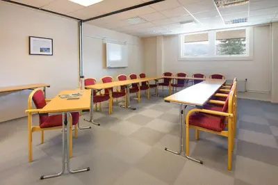 a classroom with tables and chairs and a white wall at Scandic Valdres in Fagernes