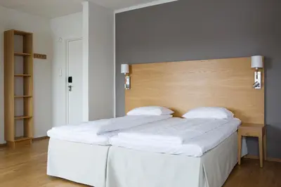 two white beds in a room with a wooden headboard at Comfort Hotel Fosna in Kristiansund