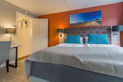 a bedroom with a large bed with blue pillows at Beito Resort Hotel in Beitostøl