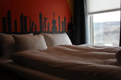 a bed with white sheets and a window in a room at Stasjonen Hotel in Lillehammer