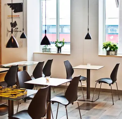 a restaurant with tables and chairs and windows at Stasjonen Hotel in Lillehammer