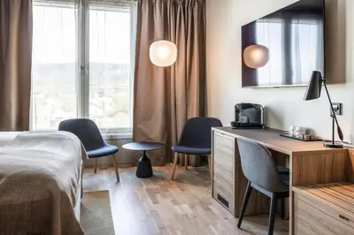a hotel room with a bed and two chairs at Quality Airport Hotel Værnes in Stjoerdal