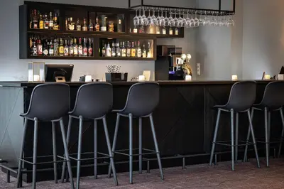 a bar with four black stools at a counter at Quality Airport Hotel Værnes in Stjoerdal