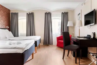 a hotel room with two beds and a desk and a red chair at Best Western Plus Hotel Bakeriet in Trondheim