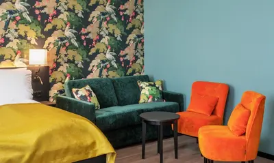 a bedroom with a green couch and two orange chairs at Thon Hotel Bristol, Bergen in Bergen
