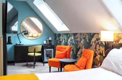 a bedroom with a bed and orange chairs and a mirror at Thon Hotel Bristol, Bergen in Bergen