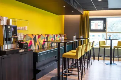 a restaurant with a bar with yellow walls and stools at Thon Hotel Bergen Airport in Bergen