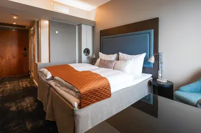 a bedroom with a large bed with an orange blanket at Clarion Hotel Bergen Airport in Bergen