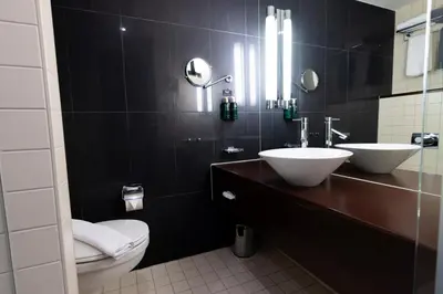 a bathroom with a toilet and two sinks and a mirror at Clarion Hotel Bergen Airport in Bergen