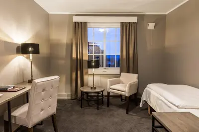a hotel room with a bed and a desk and chair at Klækken Hotel in Hønefoss