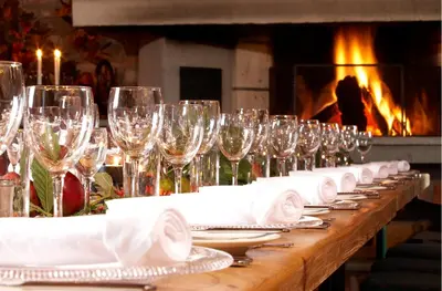 a row of wine glasses on a table in front of a fireplace at Klækken Hotel in Hønefoss
