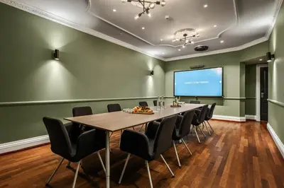 a conference room with a table and chairs and a screen at Home Hotel Bryggen in Bergen