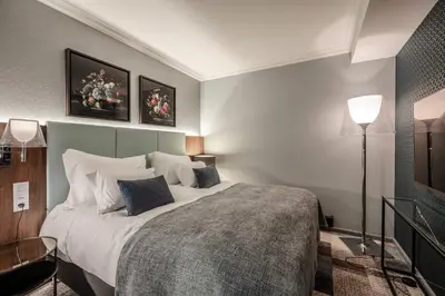 a bedroom with a large bed and two pictures on the wall at Home Hotel Bryggen in Bergen