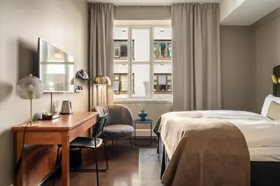 a hotel room with a bed and a desk and a window at Home Hotel Bryggen in Bergen