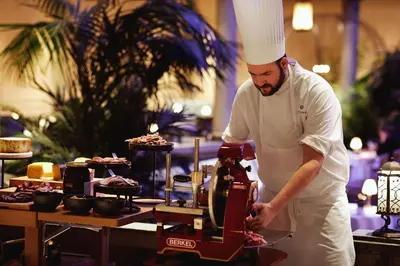 a chef standing in a kitchen preparing food at Britannia Hotel in Trondheim
