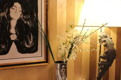 a vase with flowers in it next to a picture at Det Hanseatiske Hotel in Bergen