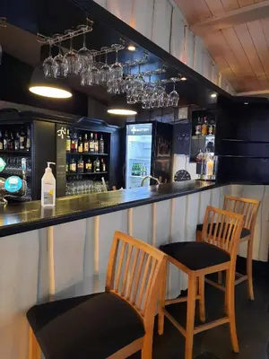 a bar with three chairs and a counter with alcohol at Hafjell Hotell in Hafjell
