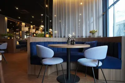 a table and two stools in a restaurant at Home Hotel Grand Olav in Trondheim