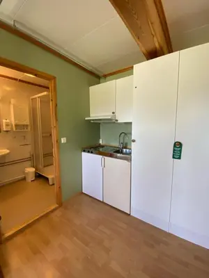 a kitchen with white cabinets and a wooden floor at Trædal Hotel in Sunndalsøra